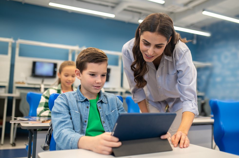 Mentor helping a student learn on a tablet